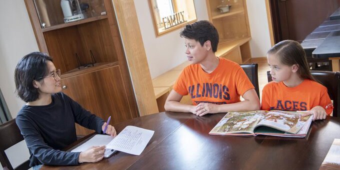 Two students speaking and a child reading a book