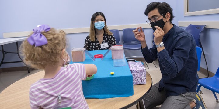 Two students working with a child at a table with obstacles