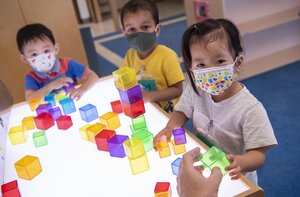 Three children at a table playing with blocks